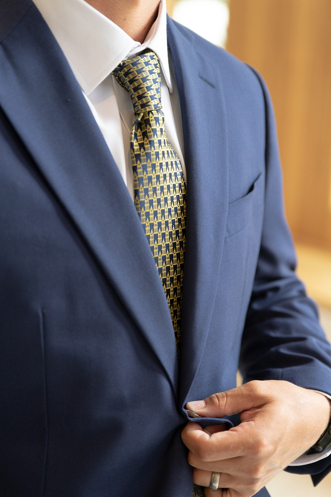 man unbuttoning jacket with blue and gold tie