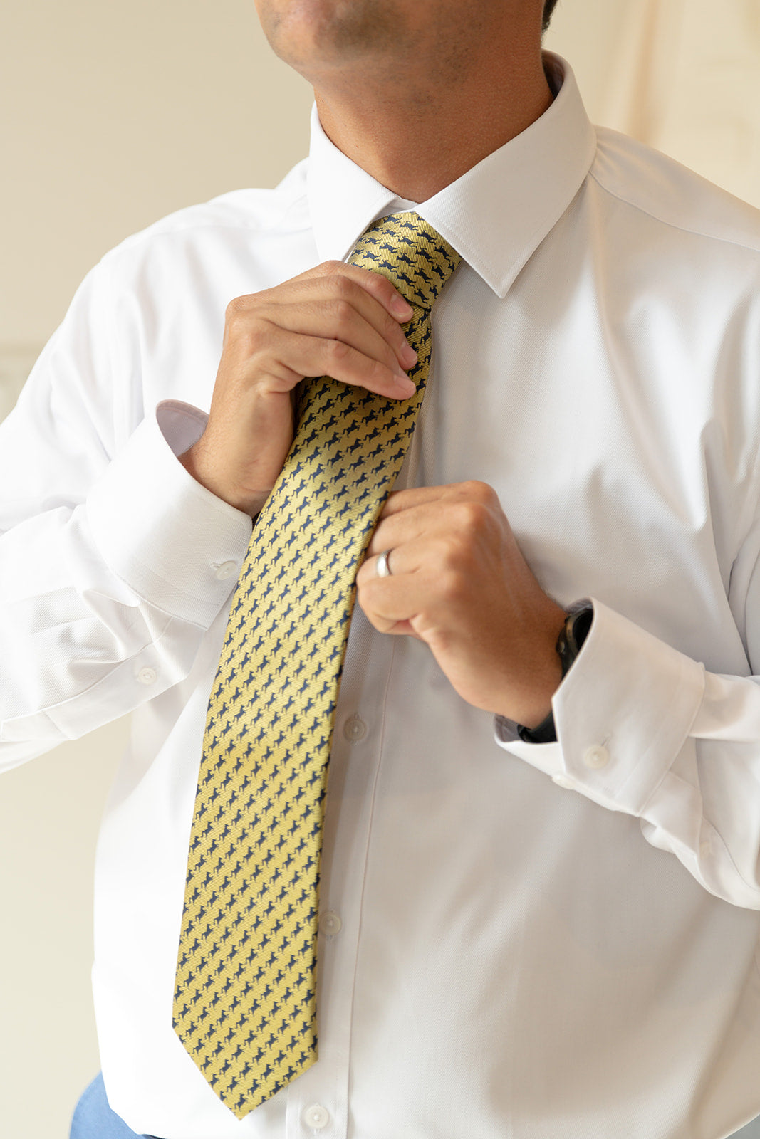 man adjusting UCO gold and navy broncho tie