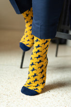 Load image into Gallery viewer, UCO gold and navy broncho sock with feet on barstool
