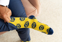 Load image into Gallery viewer, man pulling up UCO gold and navy broncho sock
